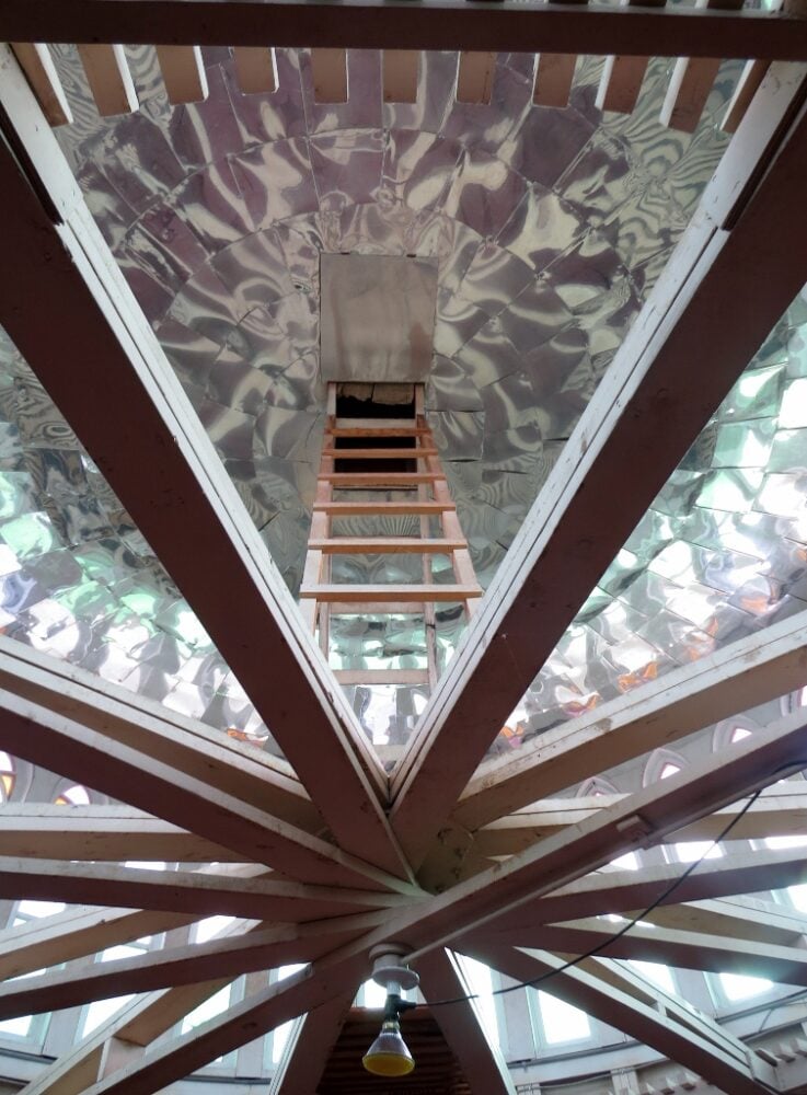 A ladder leads into the ceiling of the church, with mirrored panels either side