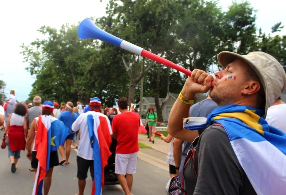 JR blowing a horn at the Tintamarre on Acadian Day in Caraquet, New Brunswick