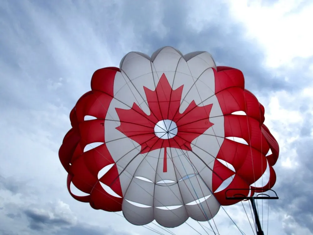 Colors of the Canadian flag on a parasailing parachute flying in the sky 