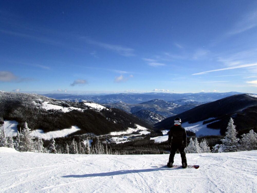 Snowboarder with mountain views at the top of Apex Ski Resort