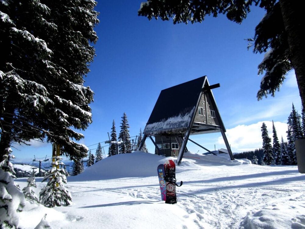 Two snowboards vertical in the snow in front of the Stocks chairlift at Apex Mountain Resort near Penticton