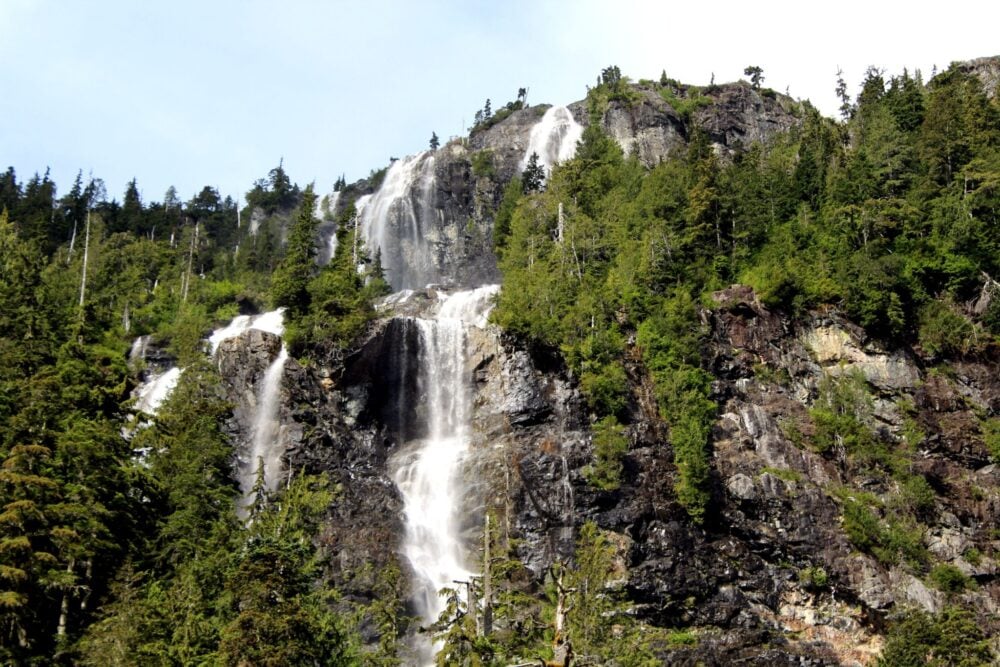 Tall cascading waterfall surrounded by forest