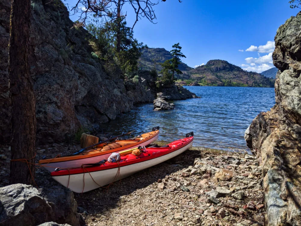 Orange and red kayaks sitting on rock shore in narrow cove on Rattlesnake Island