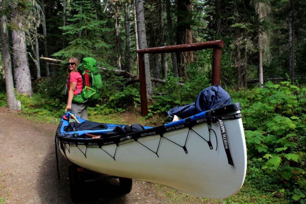 Gemma pulling white canoe on wheels along trail on the west side of Bowron Lakes Canoe Circuit