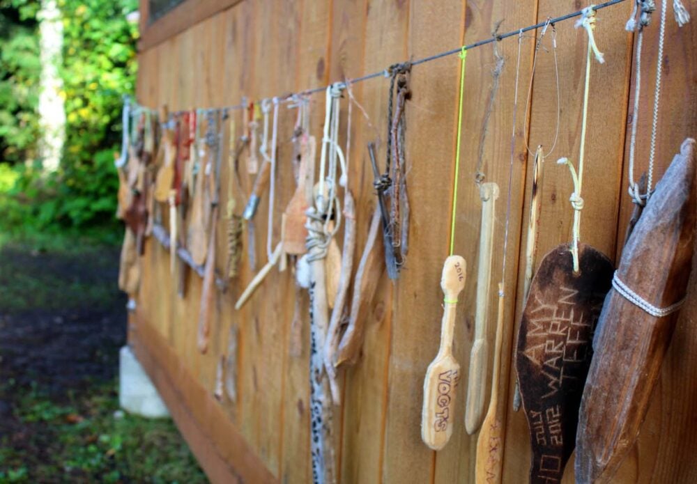 Close up of carved wooden mini canoe paddles hanging outside a wooden shelter on the Bowron Lakes Canoe Circuit