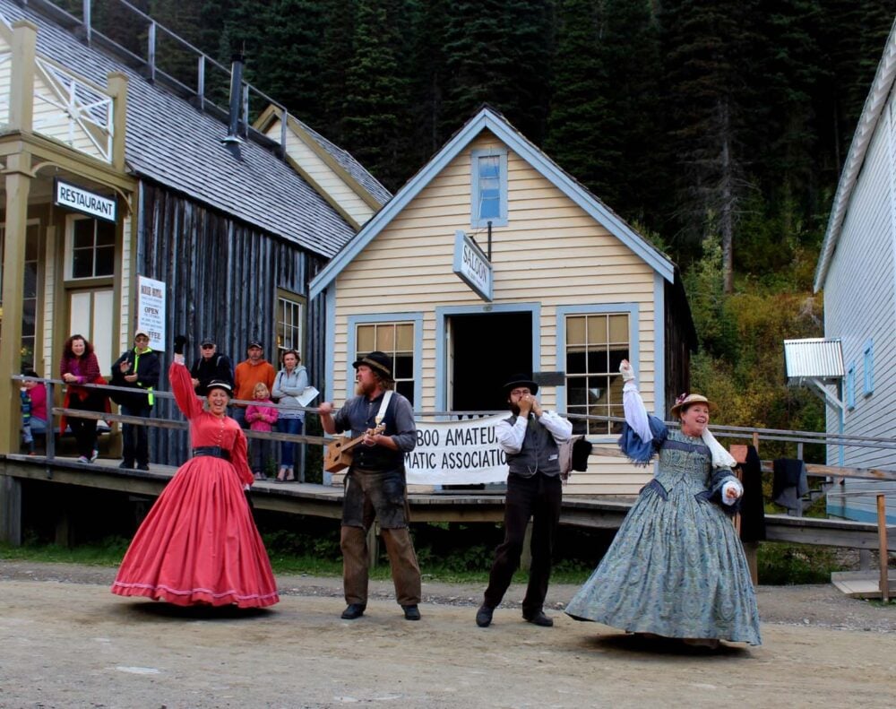 Four costumed Barkerville interpreters dancing and playing music