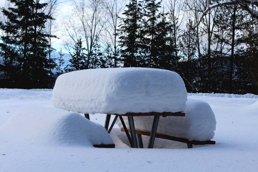 Picnic table with huge amount of snow on surface and bench