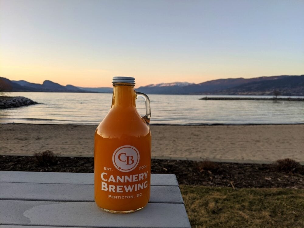 Glass grunt of beer on picnic table in front of gorgeous Okanagan Lake at sunset