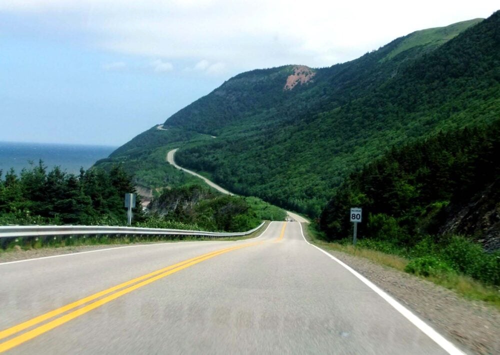 Winding road over green highlands next to the ocean - the Cabot Trail, Nova Scotia