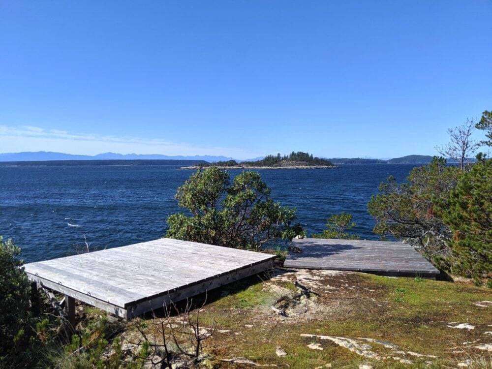 Two wooden tent pads overlooking coastal scenery