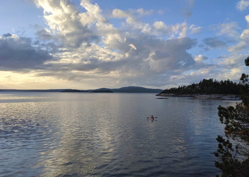 JR in kayak in distance with islands and calm ocean