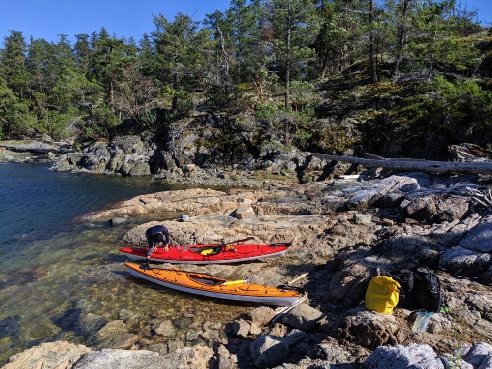 JR packing a red kayak next to shore