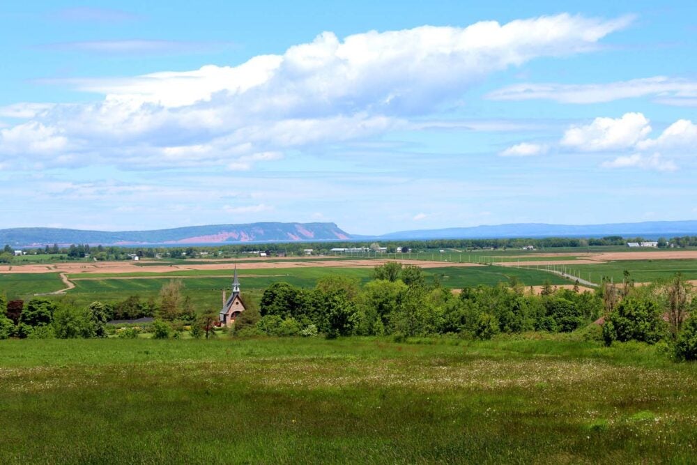 Looking towards the lush landscape of Grand Pré with grassy fields, meadows and marshland, with Memorial Church