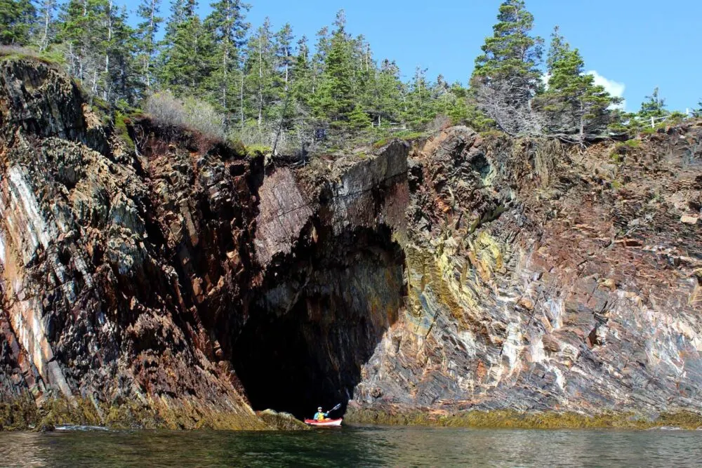 Kayaker leaving one of the sea caves at Oven Natural park, Nova Scotia