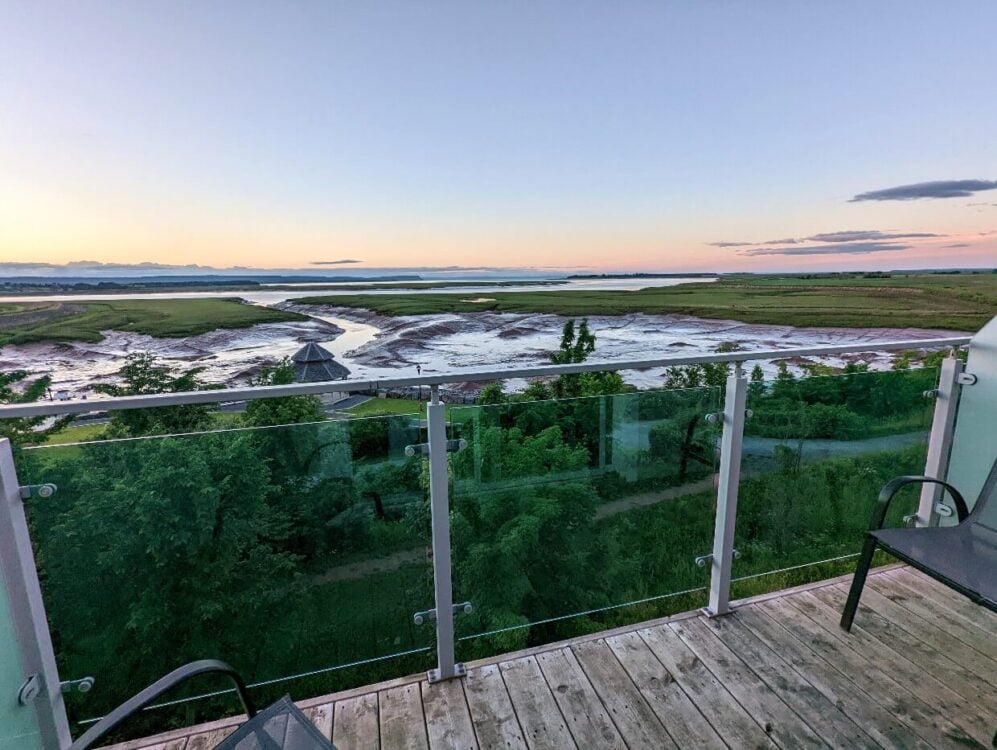 View from Wolfville Microboutique Living patio towards Minas Basin at sunset, with orange colours in the sky and the agricultural dykes visible below