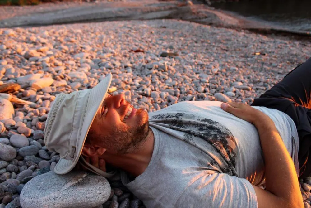 JR lying in golden hour sunshine on rocky Fishing Cove beach