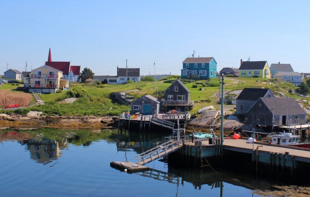 Looking back on a Nova Scotia fishing village with brightly coloured houses dotted on hill near wharf