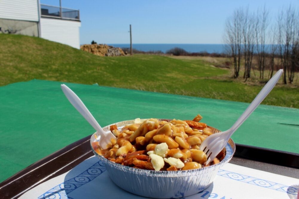 Tin foil container filled with fries, gravy and cheese curds (poutine)