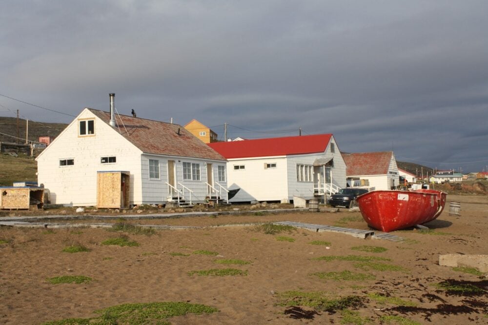 Red boat in front of white wooden houses in Iqaluit, Nunavut