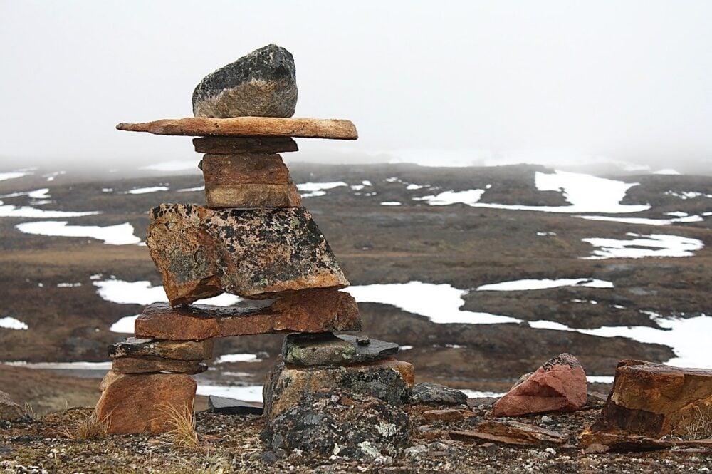 Inukshuk in front of patches of snow in Iqaluit, Nunavut