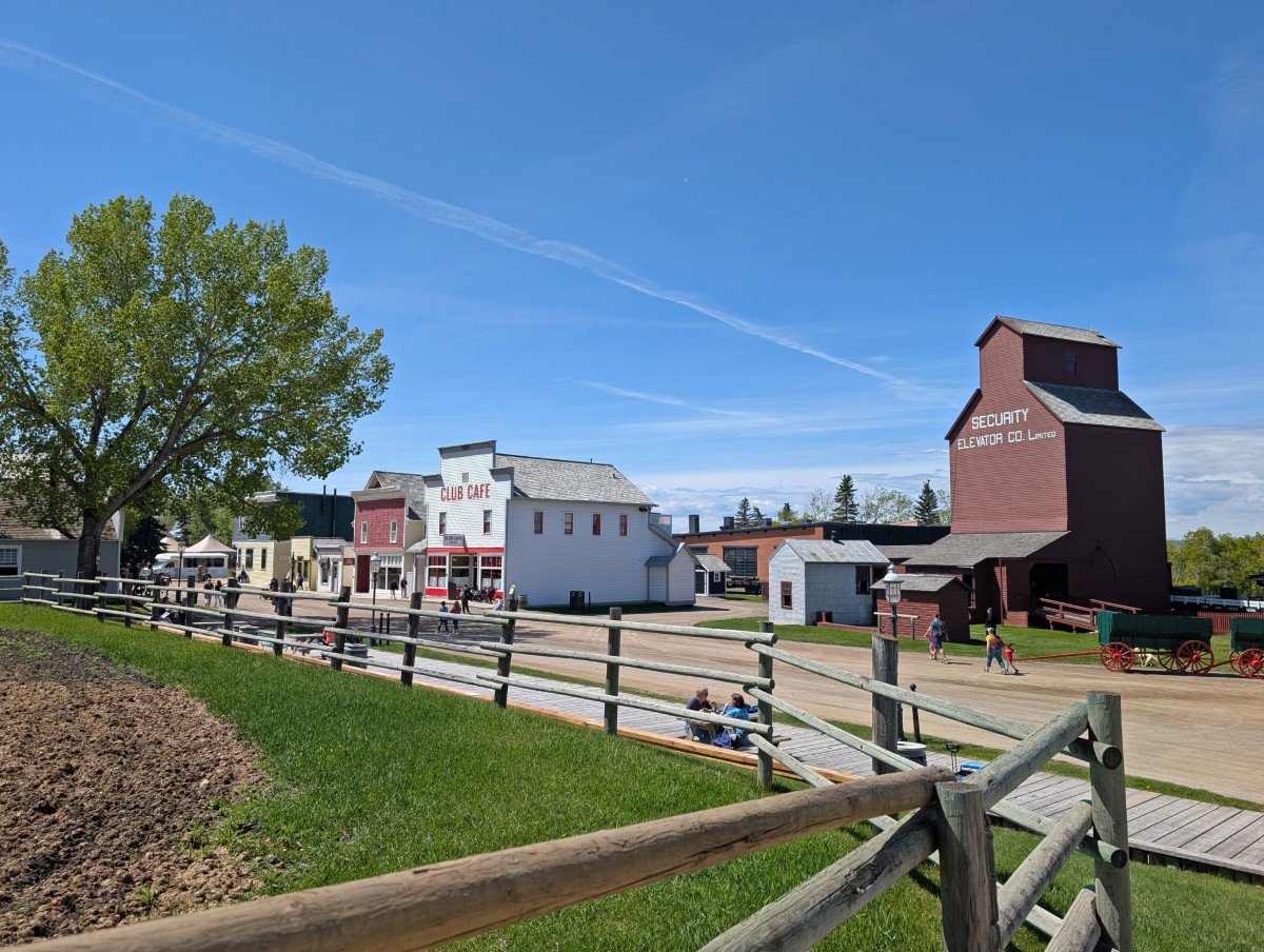 Fence view of Historic Prairie Town in Heritage Park, with restored grain elevator and multiple storefronts