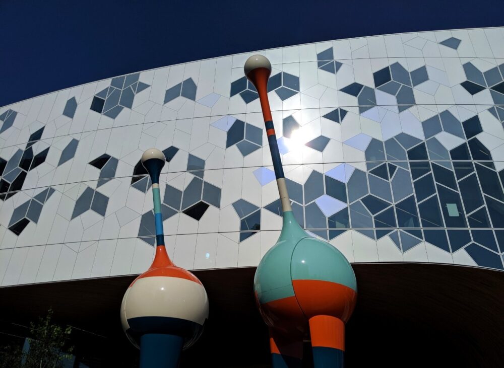 Geometric patterned building with brightly coloured art sculptures in front