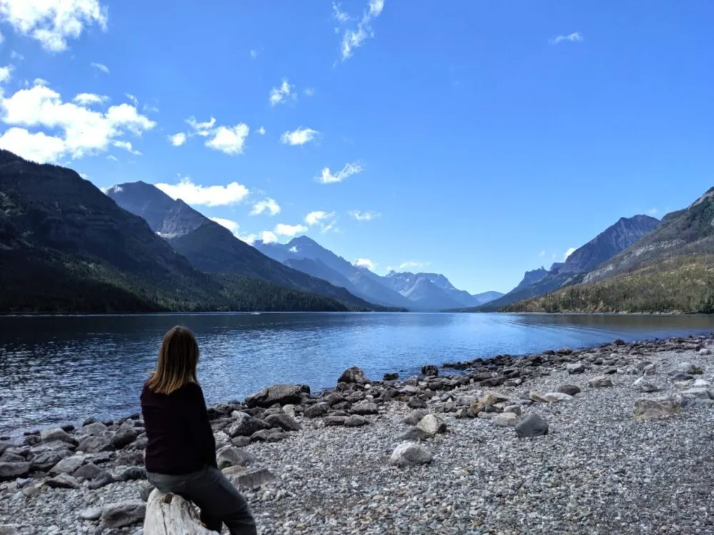 Gemma sits on a log looking out to beautiful lake views in Waterton National Park