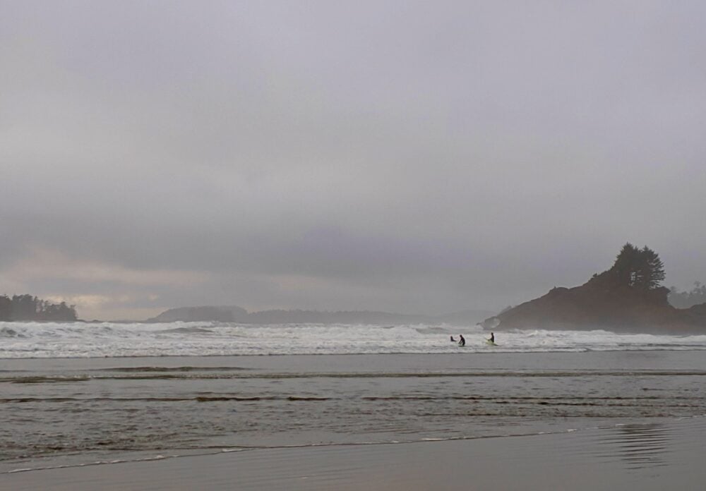 Three people surfing in big waves at Cox Bay, Tofino