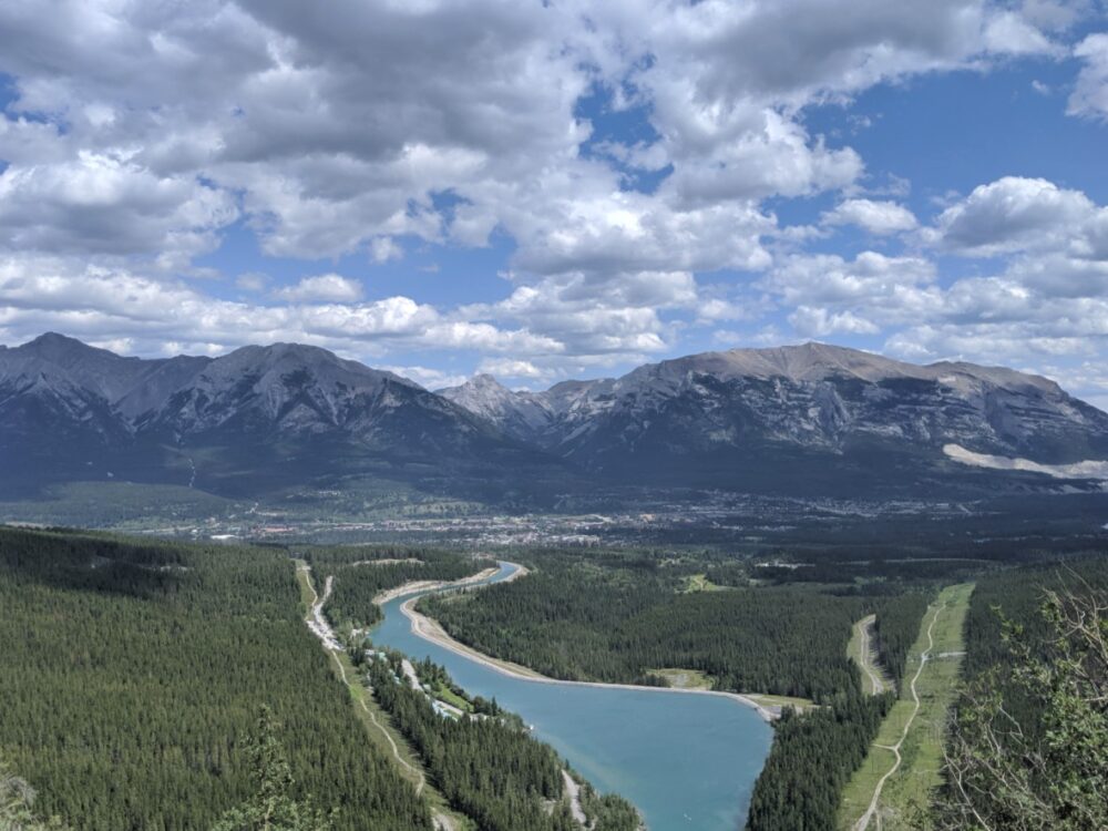 Looking down at Canmore from road viewpoint, with lake in foreground, mountain backdrop