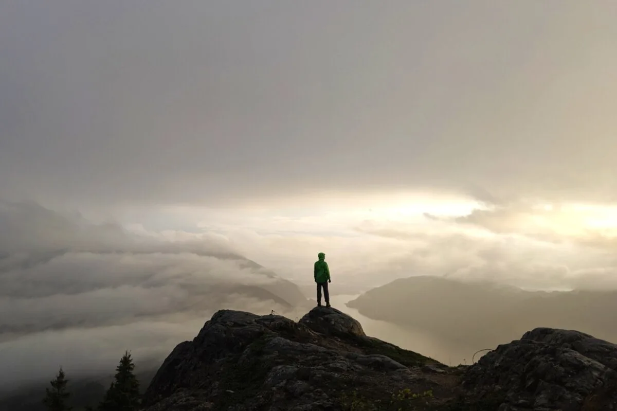 JR standing on Tin Hat Mountain with mist and sun setting behind