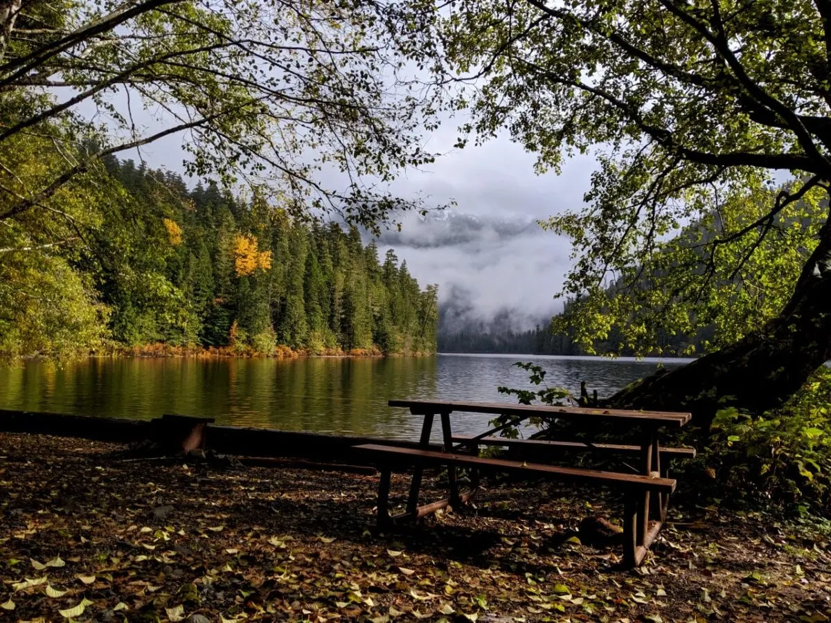 A picnic table in front of a still lake with mountain peaks in the background at Schoen Lake Campground, a great place to go camping in BC without a reservation