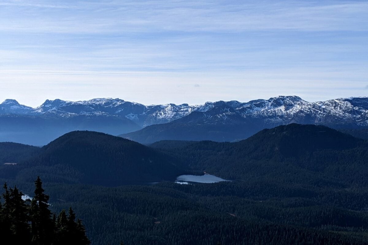 Snow capped mountainous peaks with alpine lakes nested in the forest below