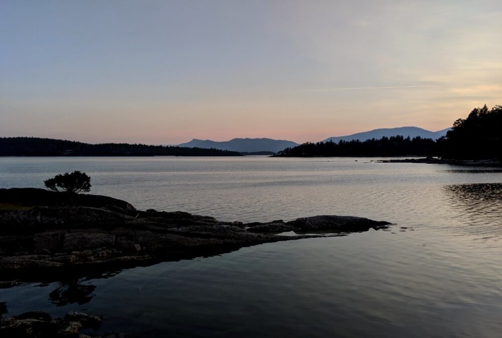 Calm ocean at sunset, with islands scattered around the horizon