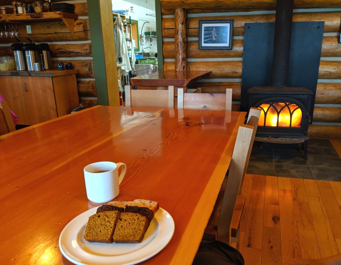 Plate of cake slices and cup of tea in front of the fire at Assiniboine Lodge