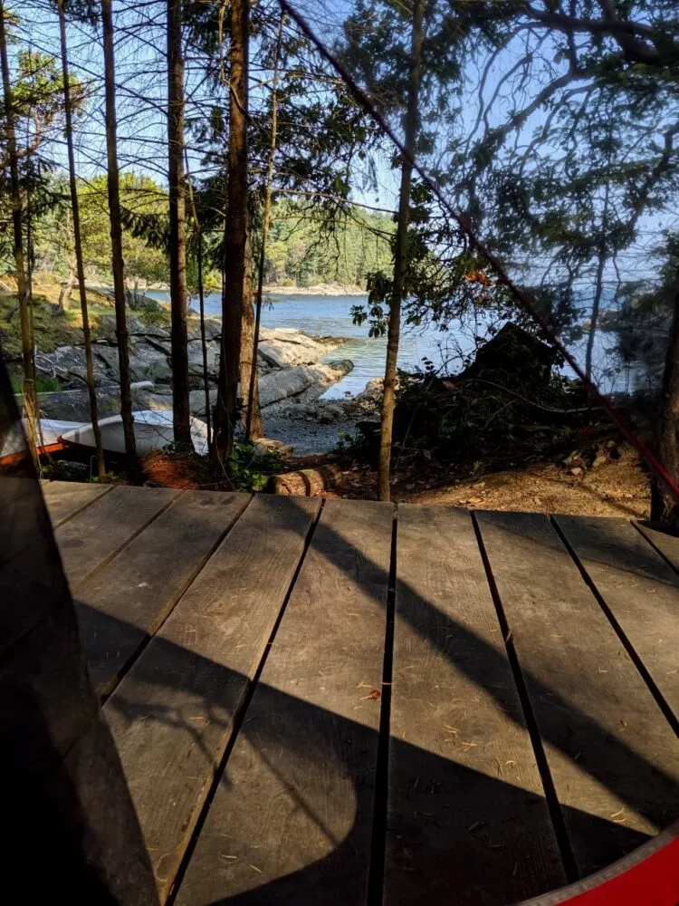 View through open tent door of wooden tent pad edge and beach