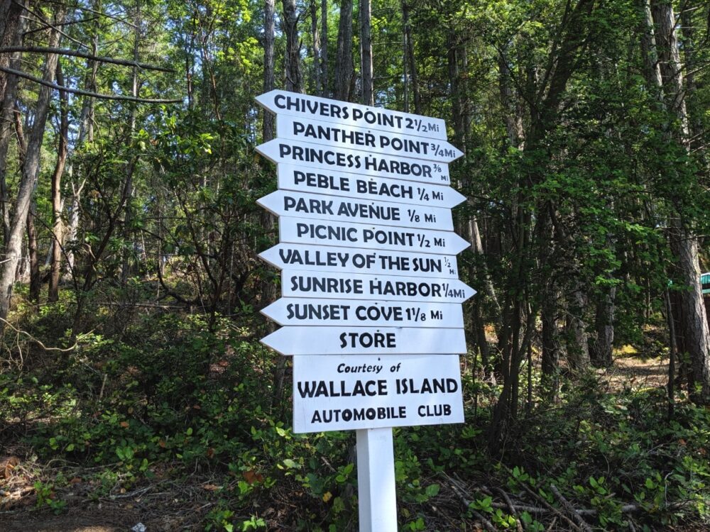 White signs with black text pointing the way to different areas of Wallace Island