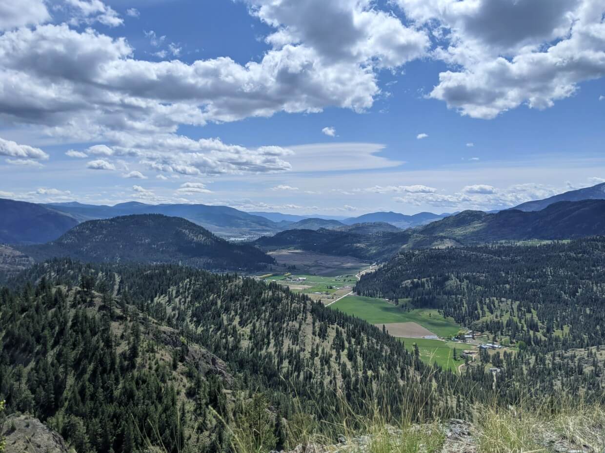 View across forested hills with fields below, from Guys Cache hike
