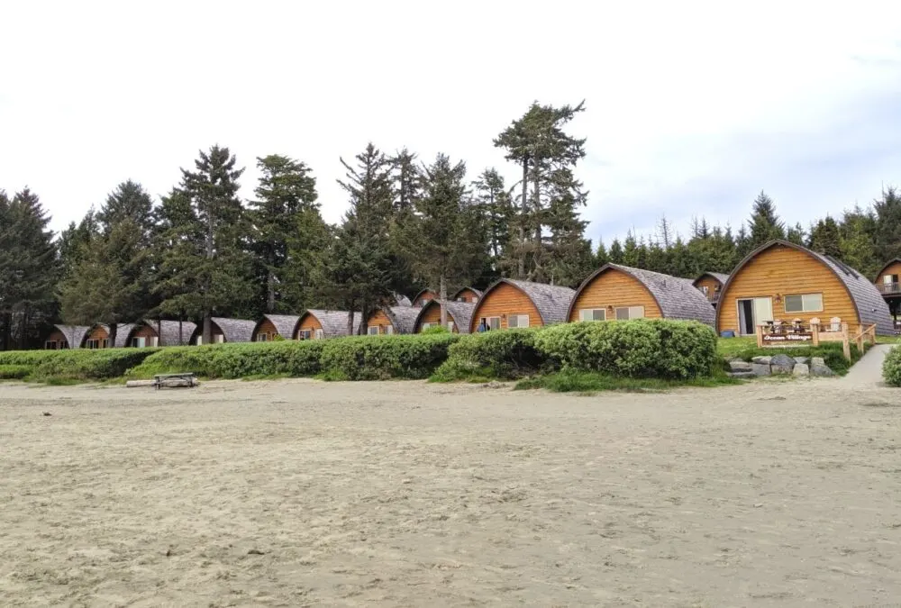 Line of beehive cabins situated behind the sands of Mackenzie beach at Ocean Village in Tofino, one of the best places to stay in Tofino