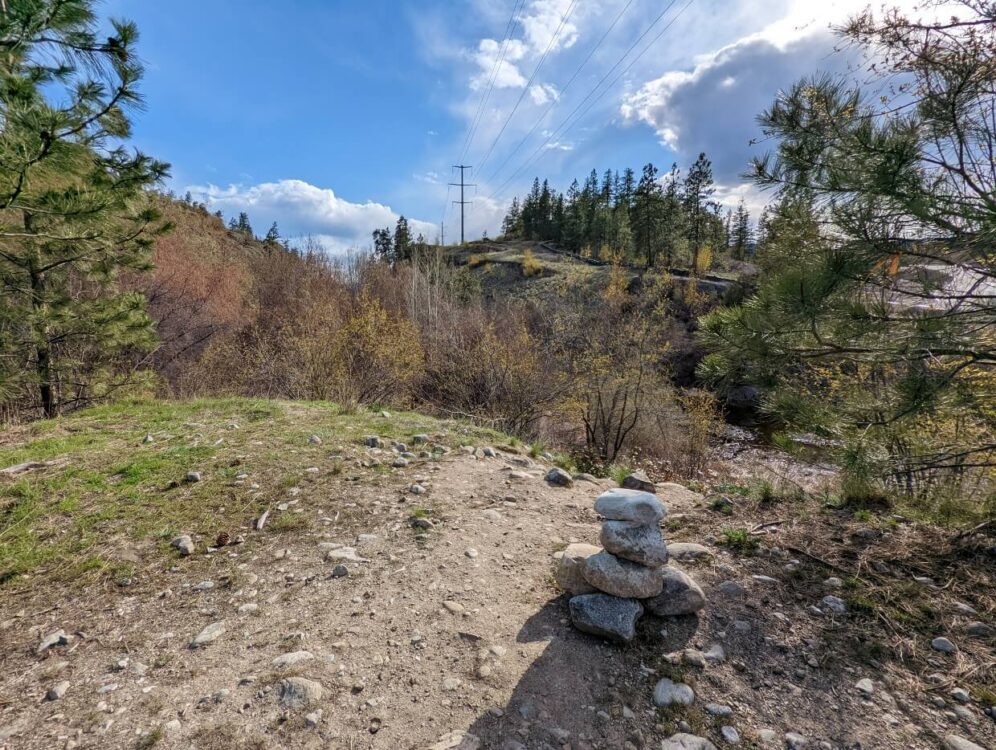 Rock cairn next to dirt hiking path at edge of Skaha Bluffs Provincial Park in Penticton