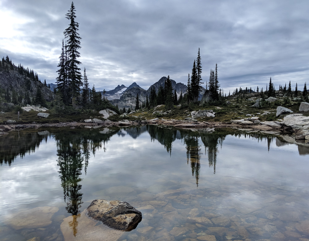 Transquil lake reflections with mountains and rocks in Gwillim Lakes