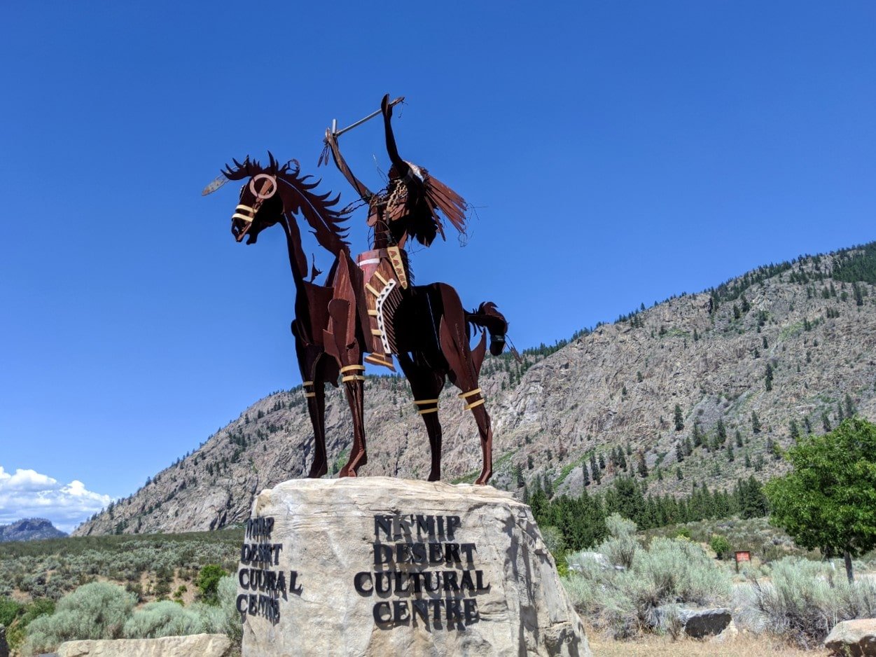 Metal sculpture of horse and rider on rock plinth at the Nk'Mip Desert Cultural centre
