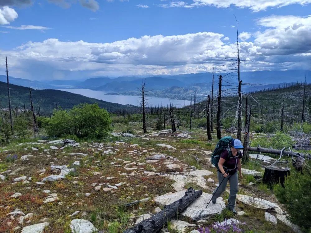 Gemma hiking on Divide Lake trail with panoramic views of Okanagan Lake and surrounding mountains behind