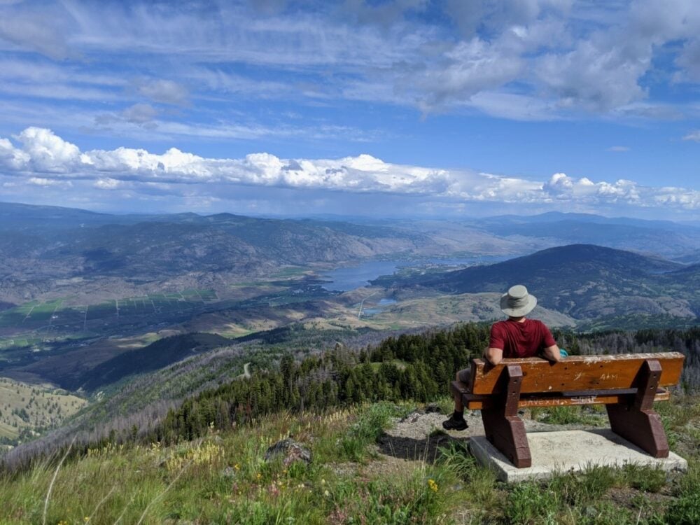 JR at on bench looking out to elevated view of Osoyoos set into rolling hills and vineyards