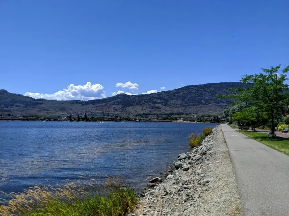 Paved cycle path next to Osoyoos Lake with rolling hills behind