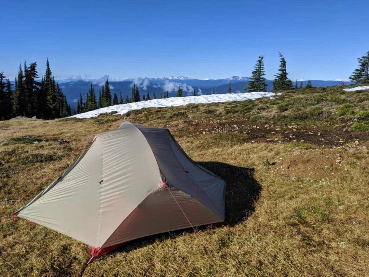 Set up tent in alpine area above Murtle Lake with snow capped mountains in backgound