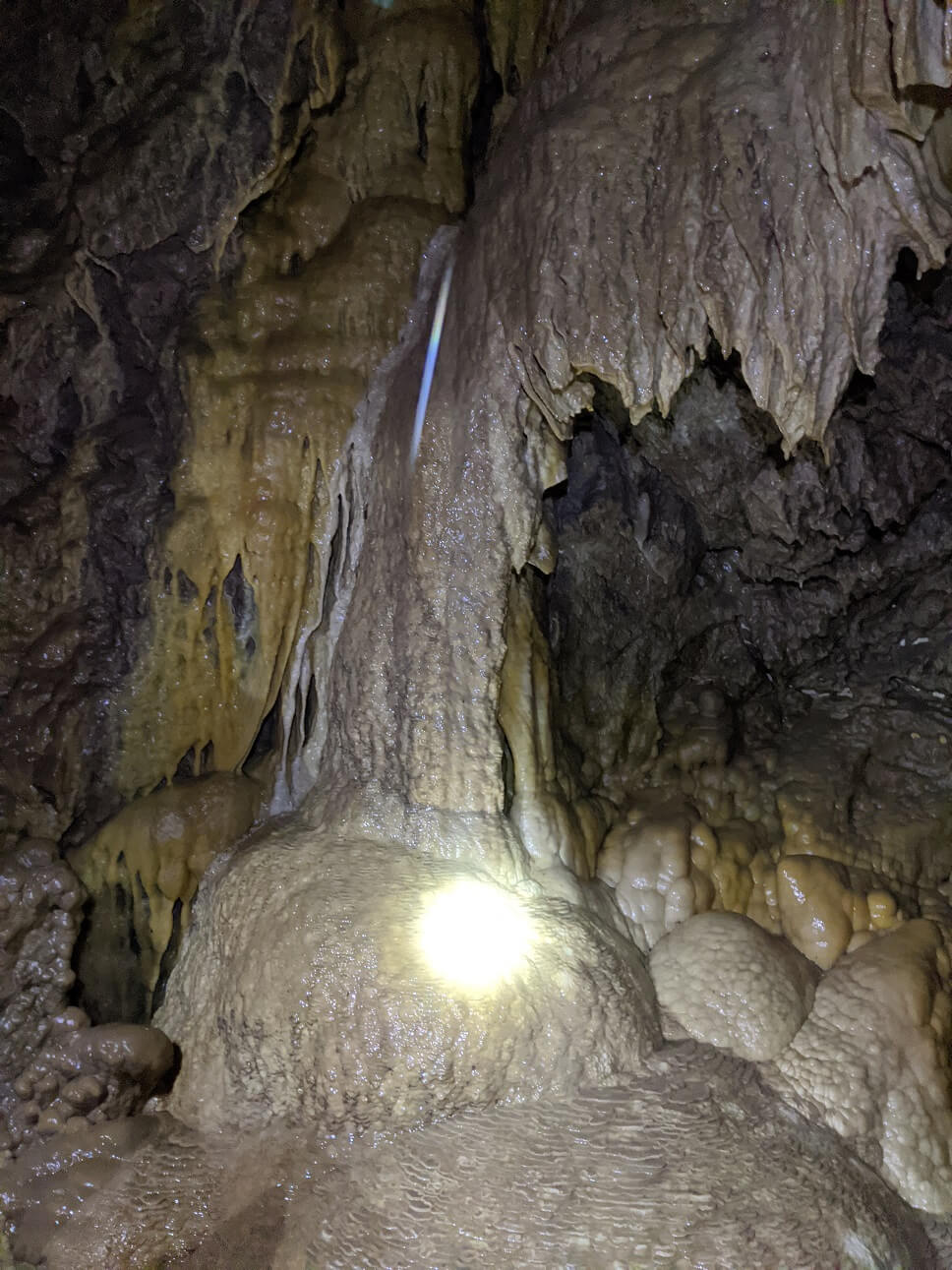 Low lighting view of light cream and yellow coloured cave formations in Rat's Nest cave system near Canmore