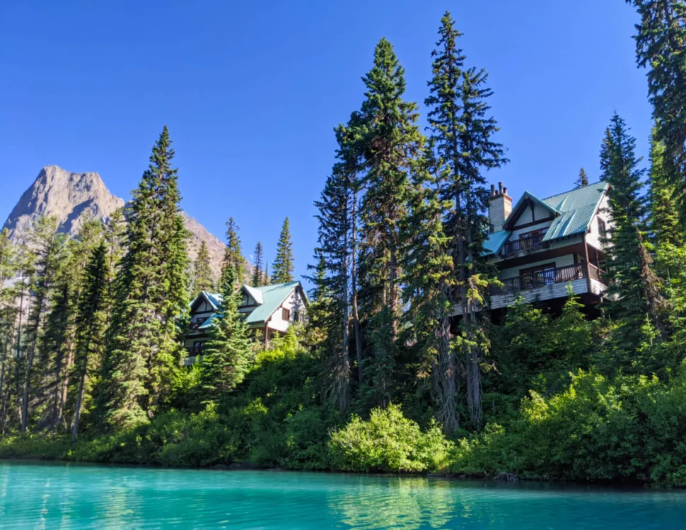 Two floor cabins on edge of Emerald Lake with tall trees and turquoise coloured lake water