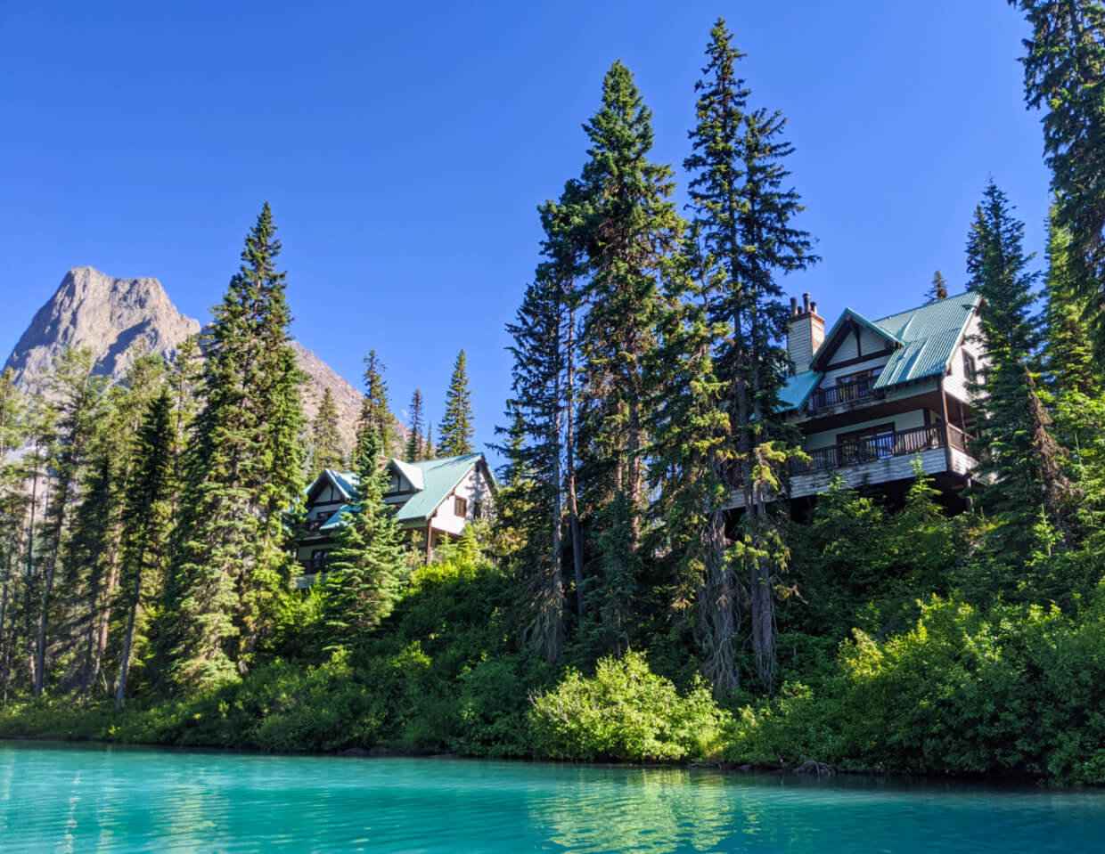 Lake view looking up at multiple floor cabins at Emerald Lake Lodge, with forest in foreground