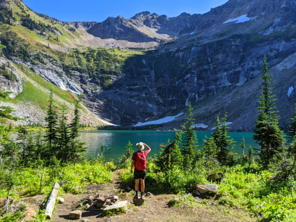 Back view of JR standing in front of turquoise lake, with high rock amphitheater rising behind