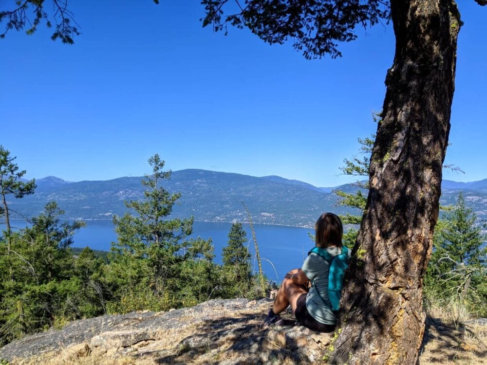 Gemma sat in front of shady tree with elevated view of Okanagan Lake